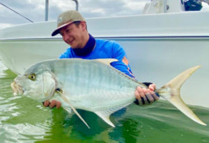 man holding a golden trevally caught on fly in Hervey Bay, Qld Australia